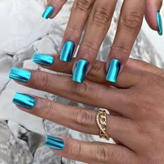 two hands with blue manies and gold rings on them, one holding a ring