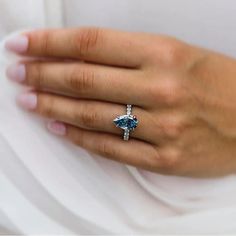 a woman's hand wearing a ring with a blue topazte and diamonds