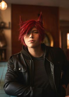 a young man with red hair wearing a leather jacket and devil horns on his head