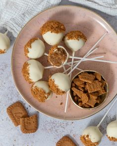 a pink plate topped with cookies and marshmallows next to two spoons