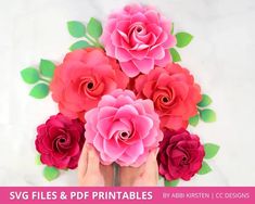 paper flowers are being held by hands with green leaves on the bottom and pink roses in the middle