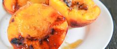 three grilled peaches on a white plate