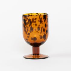 a brown and black glass cup sitting on top of a wooden stand