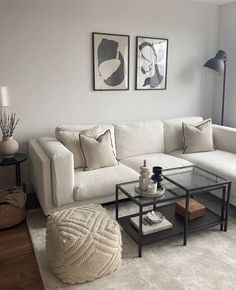 a living room with white couches and two pictures on the wall above them, along with a coffee table