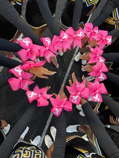 a group of people standing in a circle with pink bows on their heads and hands