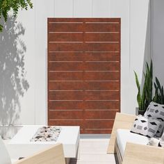 an outdoor living area with two white couches and a wooden screen in the background