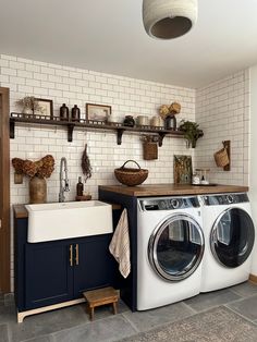 a washer and dryer in a room with white bricks on the wall behind them