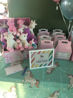 a table topped with lots of pink and purple stuffed animals next to boxes filled with unicorns