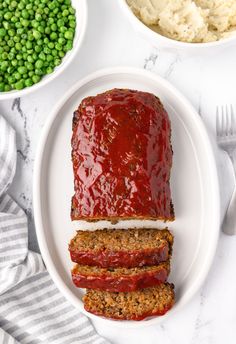 meatloaf on a plate with mashed potatoes and peas