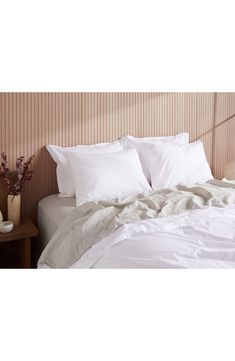 a bed with white sheets and pillows on it