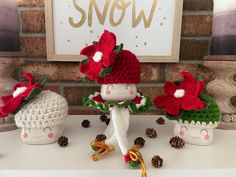 three knitted christmas decorations sitting on top of a white table next to a brick wall