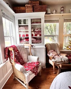 a living room filled with furniture next to a window covered in red and white blankets