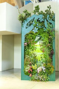 an open door with plants and flowers on it in the middle of a room filled with white walls