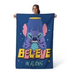 a woman holding up a blue poster with an image of a cartoon character and the words believe in aliens