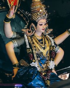 a woman dressed in an elaborately decorated costume and holding a red object above her head