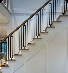 a white staircase with wooden handrails and black railing on the bottom floor in a home