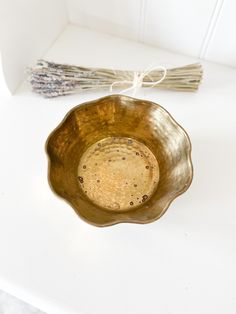 a metal bowl sitting on top of a white table next to a bundle of sticks