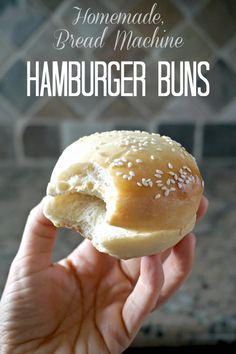 a hand holding a hamburger bun with sesame seeds on it and the words homemade bread machine hamburger buns