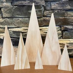 three wooden trees sitting on top of a table next to a stone wall