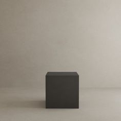 a black square object sitting on top of a white floor in front of a wall