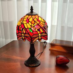 a lamp sitting on top of a wooden table next to a computer mouse and window