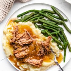 a plate with mashed potatoes, green beans and gravy on the side