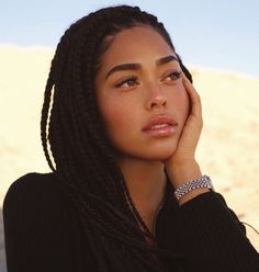 a woman with long braids is posing for a photo in front of the desert