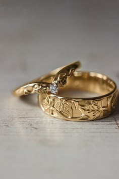 two gold wedding rings sitting on top of each other