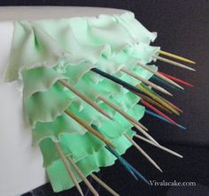 there is a cake decorated with green icing and colorful sticks sticking out of it