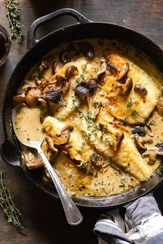 a skillet filled with chicken and mushrooms covered in gravy on top of a wooden table