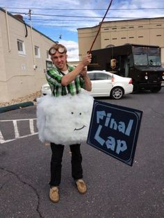 a man is holding a sign that says final lap and wearing goggles while standing in the parking lot