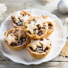 several small pies on a white plate with silver ornaments in the backgroud