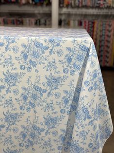 a blue and white table cloth with flowers on it in front of bookshelves