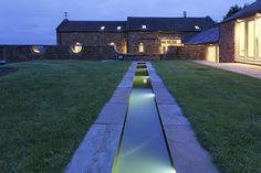 a house that is lit up at night with lights on the windows and reflecting in the water