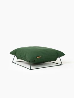 a green pillow sitting on top of a black metal frame stand with a white background