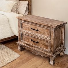 a wooden dresser sitting on top of a hard wood floor next to a white bed