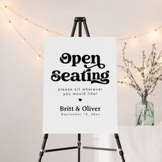 an open seating sign in front of a white wall with string lights on the side