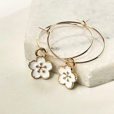 Cute hoop earrings featuring cherry blossom flower charms. Mini enamel flowers hung from gold plated hoops. Ideal for the summer or any flower lover. Complete your boho look by mixing with other ear huggies and studs. Your earrings will arrive tastefully packaged in a velvet pouch making them an ideal gift for Valentines, birthdays or any other special occasion. Dimensions Hoops 20mm. Charms approx 8mm. Made from Enamel. Gold plate on brass. Hoops 20mm. Charms approx 8mm. Cute Hoop Earrings, Ear Huggies, Pouch Making, Enamel Flowers, Cherry Blossom Flower, Cherry Blossom Flowers, Velvet Pouch, Enamel Flower, Boho Look