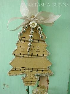 a christmas tree made out of sheet music with bells and bows hanging on a green door