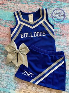 a blue and silver cheer uniform with a bow on the side, sitting on a wooden floor