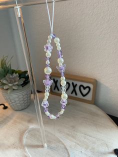 a necklace is hanging on a stand next to a potted plant