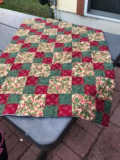 a quilted table cloth sitting on top of a picnic table with red and green squares