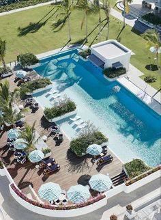 an aerial view of a swimming pool surrounded by lawn chairs and umbrellas