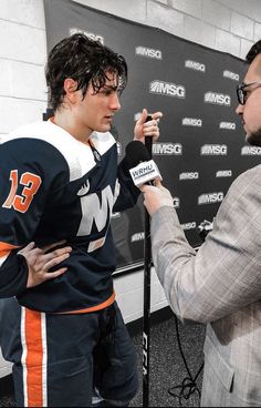 two men talking to each other in front of a microphone