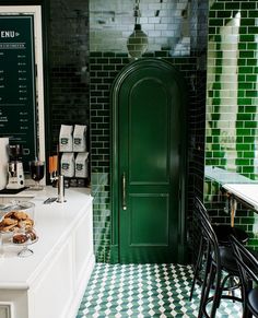 a green door in the middle of a kitchen with black and white checkered flooring