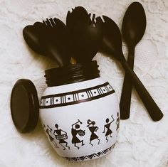 a jar with spoons and utensils in it sitting on a white surface