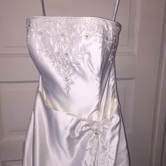 a white wedding dress hanging on a door