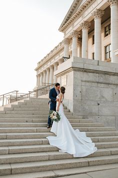 a bride and groom are standing on the steps in front of an old courthouse building