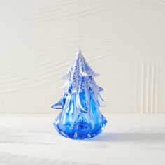 a blue glass christmas tree sitting on top of a white table next to a wall