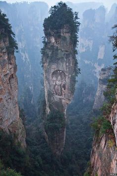 the mountains are covered in trees and rock formations, with faces carved into them on each side